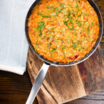 Overhead tomato and mascarpone cheese risotto with basil chiffonade served in a cooking pan.