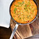 Overhead tomato and mascarpone cheese risotto with basil chiffonade served in a cooking pan.