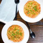 Overhead tomato and mascarpone cheese risotto with basil chiffonade served in white bowls.