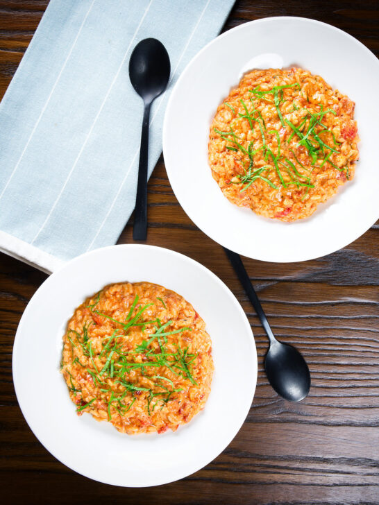 Overhead tomato and mascarpone cheese risotto with basil chiffonade served in white bowls.