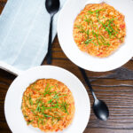 Overhead tomato and mascarpone cheese risotto with basil chiffonade served in white bowls.
