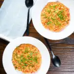Overhead tomato and mascarpone cheese risotto with basil chiffonade served in white bowls.