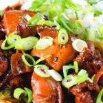 Close-up Vietnamese coconut caramel chicken served with jasmine rice and spring onions.