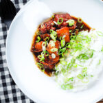 Overhead Vietnamese coconut caramel chicken served with jasmine rice and spring onions.