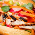 Close-up Vietnamese-influenced chicken banh mi sandwiches on a French baguette.
