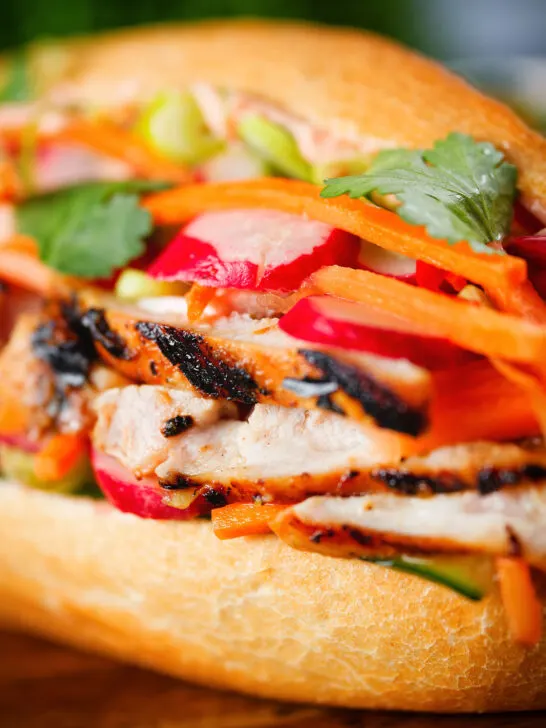 Close-up Vietnamese-influenced chicken banh mi sandwiches on a French baguette.