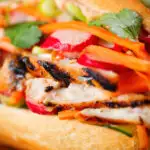 Close-up Vietnamese-influenced chicken banh mi sandwiches on a French baguette.