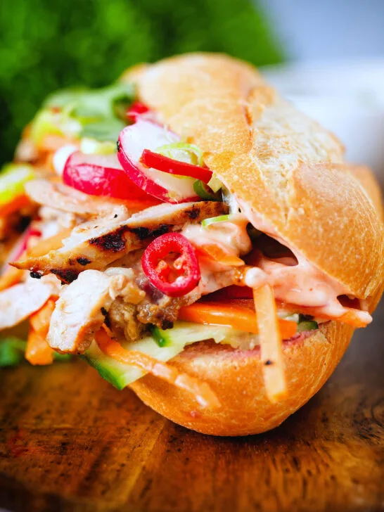 Close-up Vietnamese-influenced chicken banh mi sandwiches with quick pickles on a French baguette.