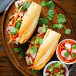 Overhead Vietnamese-influenced chicken banh mi sandwiches on a French baguette.