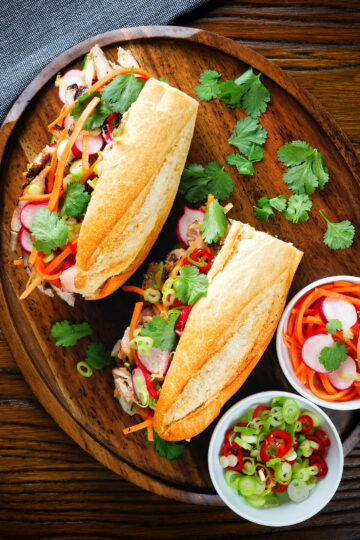Overhead Vietnamese-influenced chicken banh mi sandwiches on a French baguette.