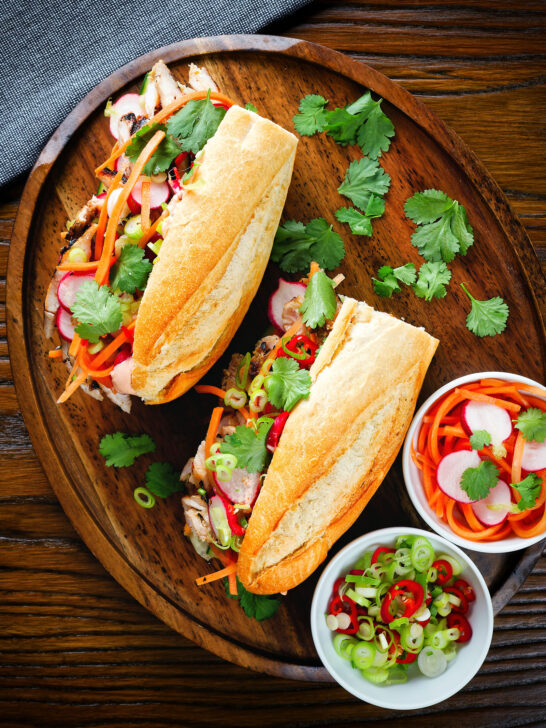 Overhead Vietnamese-influenced chicken banh mi sandwiches on a French baguette.