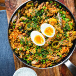 Overhead smoked mackerel kedgeree (rice) served with boiled egg in a cooking pan.