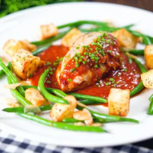 Chicken breast in a spicy tomato sauce served with Parmentier potatoes and green bean amandine.