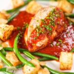 Chicken breast in tomato sauce served with Parmentier potatoes and green bean amandine.