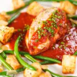 Chicken breast in tomato sauce served with Parmentier potatoes and green bean amandine.