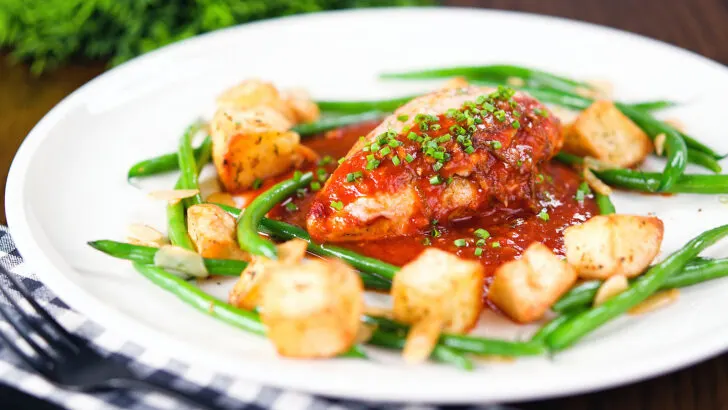 Chicken breast in a spicy tomato sauce served with Parmentier potatoes and green bean amandine.