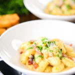 Creamy gnocchi carbonara with pecorino cheese and fresh parsley served with garlic bread.