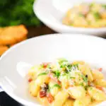 Creamy gnocchi carbonara with pecorino cheese and fresh parsley served with garlic bread.