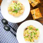 Overhead creamy gnocchi carbonara with pecorino cheese and fresh parsley served with garlic bread.