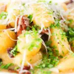 Close-up creamy gnocchi carbonara with pecorino cheese and fresh parsley.