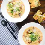 Overhead creamy gnocchi carbonara with pecorino cheese and fresh parsley served with garlic bread.