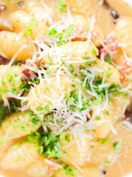 Close-up overhead creamy gnocchi carbonara with pecorino cheese and fresh parsley.