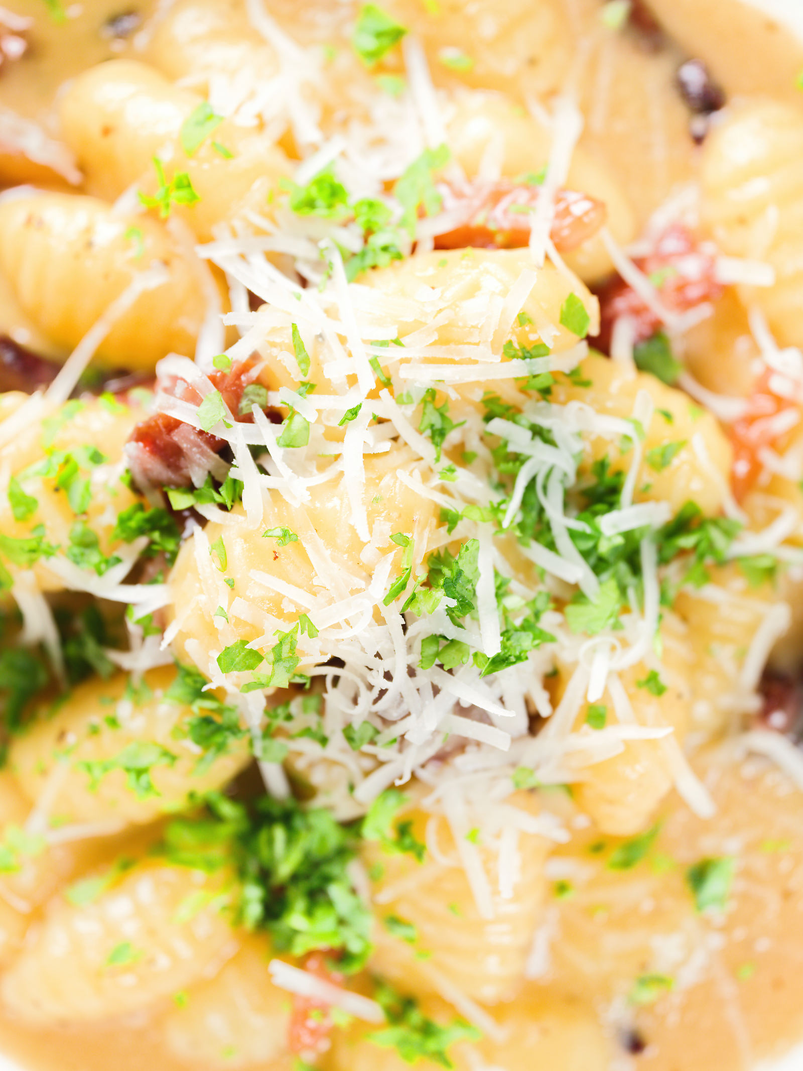 Close-up overhead creamy gnocchi carbonara with pecorino cheese and fresh parsley.