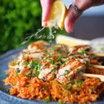 Lemon wedge being squeezed over Greek chicken souvlaki skewers.