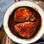 Overhead pork chops cooked in BBQ sauce served in a roasting dish.