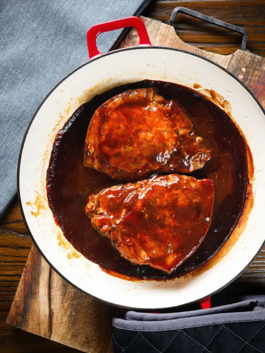 Overhead pork chops cooked in BBQ sauce served in a roasting dish.