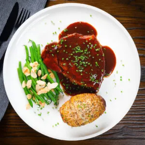 Oven baked pork chops in BBQ sauce served with green beans amandine and hasselback potato.