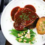 Overhead pork chops in BBQ sauce served with green beans amandine and hasselback potato.