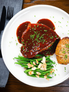 Overhead pork chops in BBQ sauce served with green beans amandine and hasselback potato.