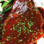 Overhead close up pork chops in BBQ sauce served with green beans amandine.