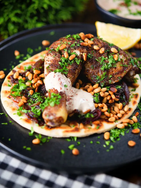 Sumac chicken musakhan with caramelised onions, pine nuts and yoghurt served on flatbread.