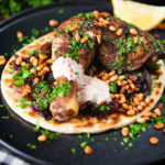 Sumac chicken musakhan with caramelised onions, pine nuts and yoghurt served on flatbread.
