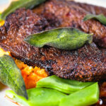 Close-up calves liver, an onion and bacon gravy, swede and carrot mash, beans and sage.