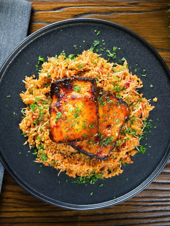 Overhead Cypriot pourgouri pilafi served with honey glazed halloumi and fresh parsley.