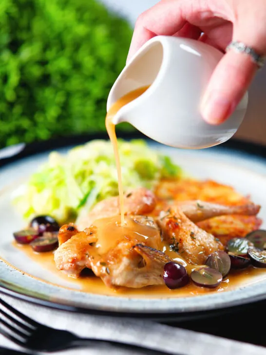 Marsala wine sauce being poured over a roasted spatchcock quail.