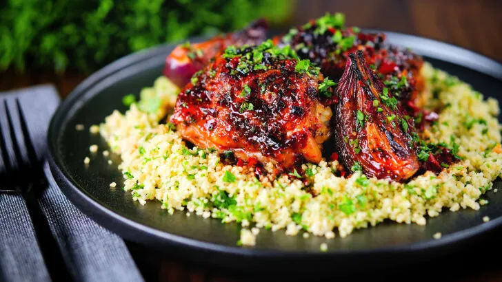 Roasted honey and harissa chicken thighs with red onions served on buttered herby couscous.