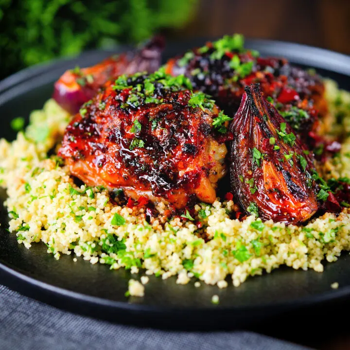 Roasted honey and harissa chicken thighs with red onions served on buttered herby couscous.
