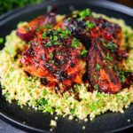Roasted honey and harissa chicken thighs with red onions and herby couscous.