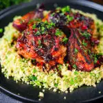 Roasted honey and harissa chicken thighs with red onions and herby couscous.