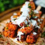 Indian salmon tikka kebab skewers served with roti and drizzled with mint raita.