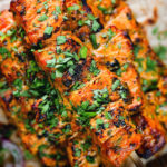 Overhead close-up Indian salmon tikka skewers served with roti and kachumber salad.