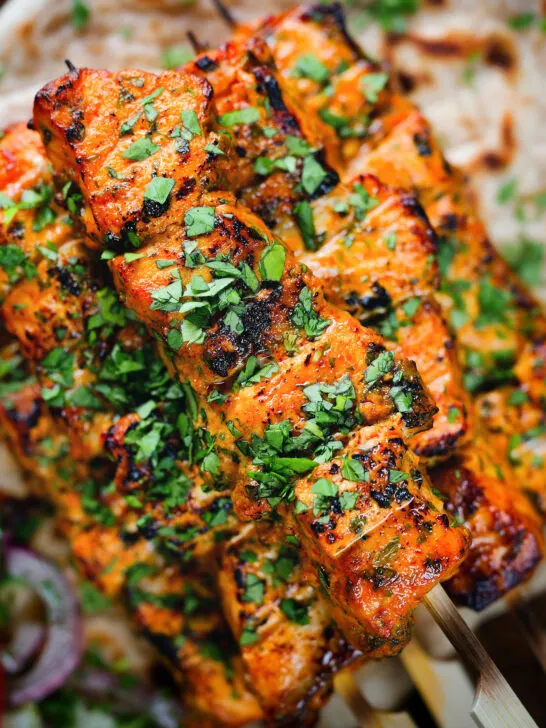 Overhead close-up Indian salmon tikka skewers served with roti and kachumber salad.