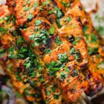 Overhead close-up Indian salmon tikka skewers served with roti and kachumber salad.