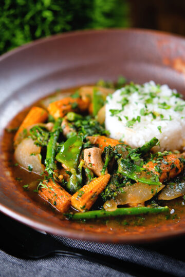 Thai chicken jungle curry (kaeng pa) served with jasmine rice and fresh herbs.