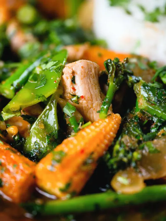Close-up Thai chicken jungle curry (kaeng pa) served with jasmine rice and fresh herbs.