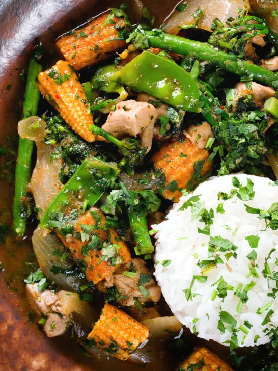 Close-up overhead Thai chicken jungle curry (kaeng pa) served with jasmine rice and fresh herbs.